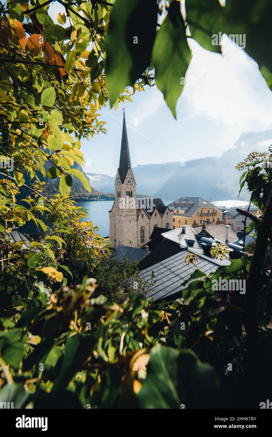 Picturesque view of ancient stone tower located in small village in Austria near lake and surrounded by mountains framed by green leaves Stock Photo