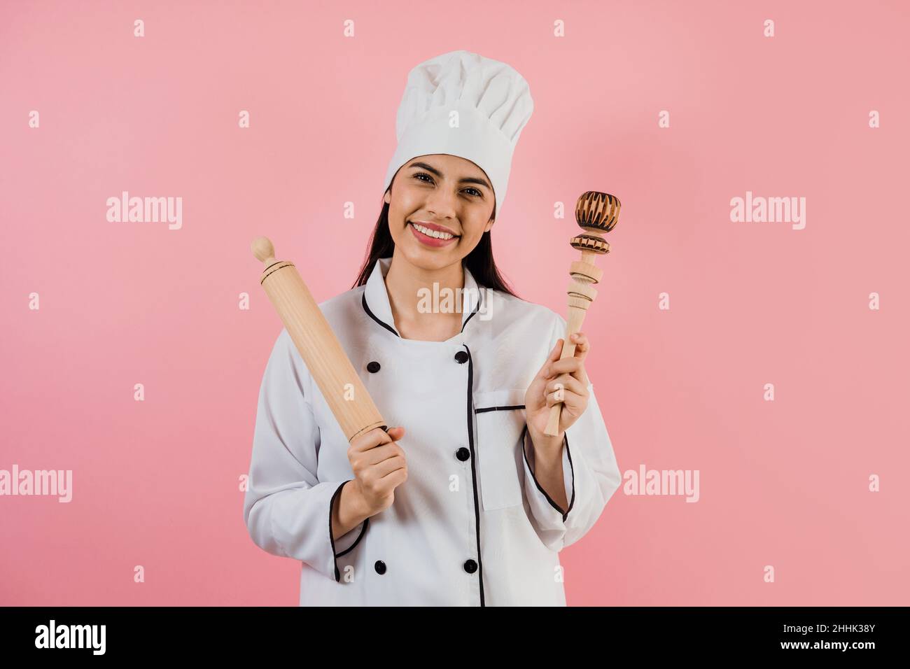 Portrait of young latin woman chef on a pink background in latin america Stock Photo