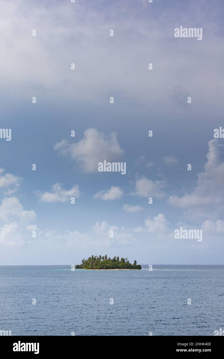 A lone tropical island sits in the Caribbean Sea under a partly cloudy sky Stock Photo