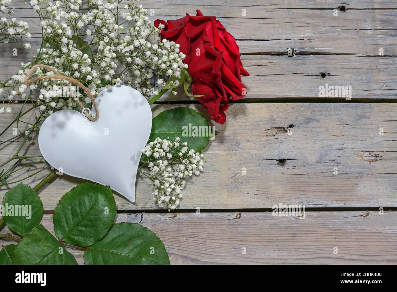 Red rose and a white heart on rustic wooden planks, romantic greeting card for Valentine's Day or Mother’s Day and for all who are loved, copy space, Stock Photo