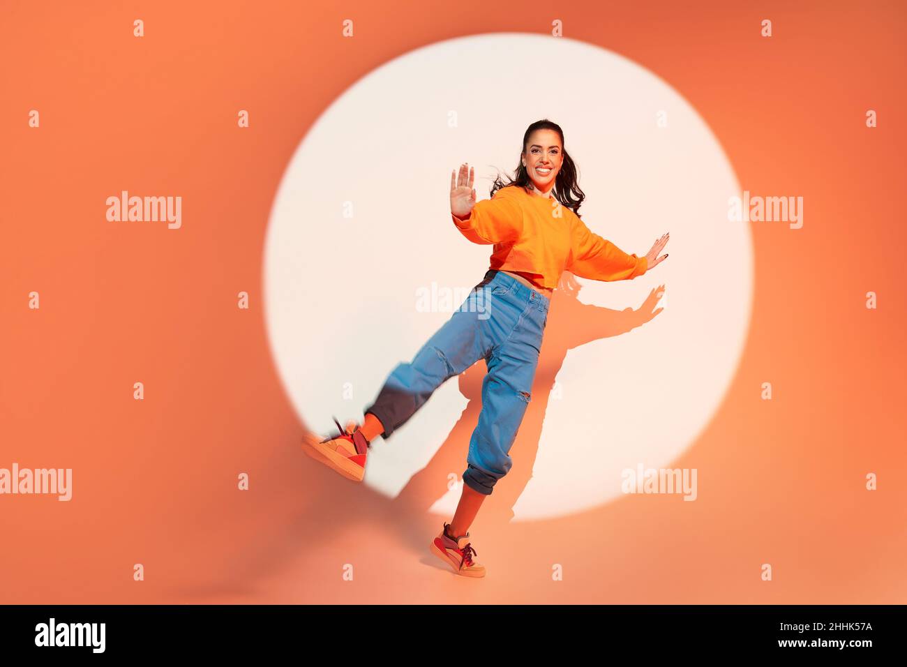 Energetic happy female dancer jumping with raised leg and outstretched