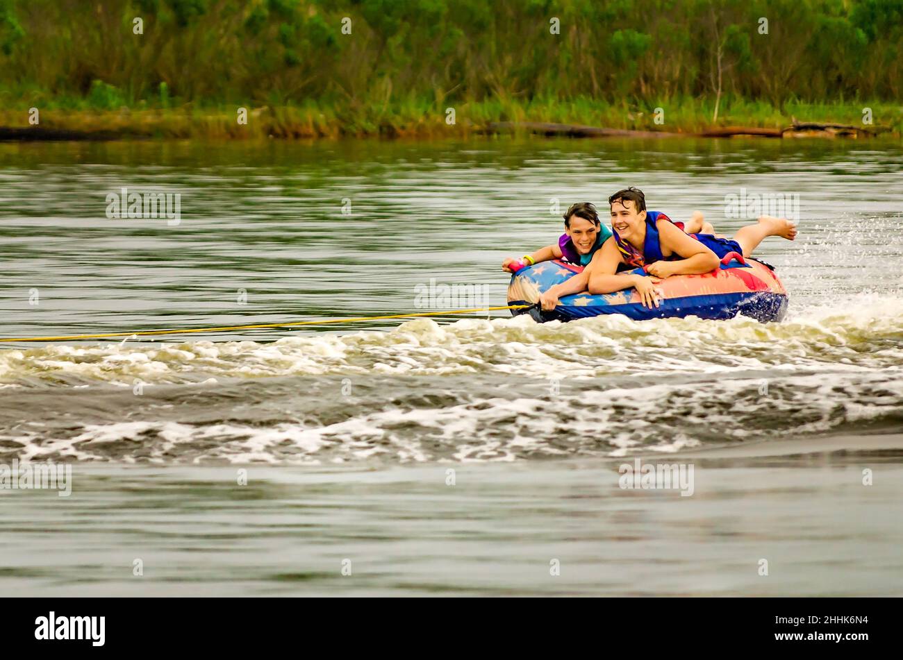 Teenage boys ride an inner tube pulled by a boat, May 1, 2016, in Bayou La Batre, Alabama. Boat tubing is a popular pastime on the Gulf Coast. Stock Photo