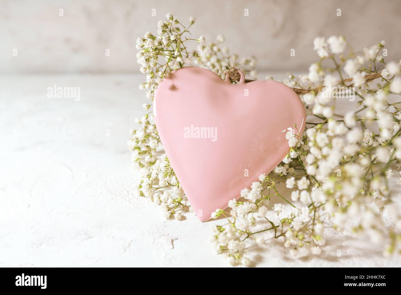 Rose colored heart shape and white gypsophila flowers on a light rustic background, love concept for valentines od mothers day, copy space, selected f Stock Photo