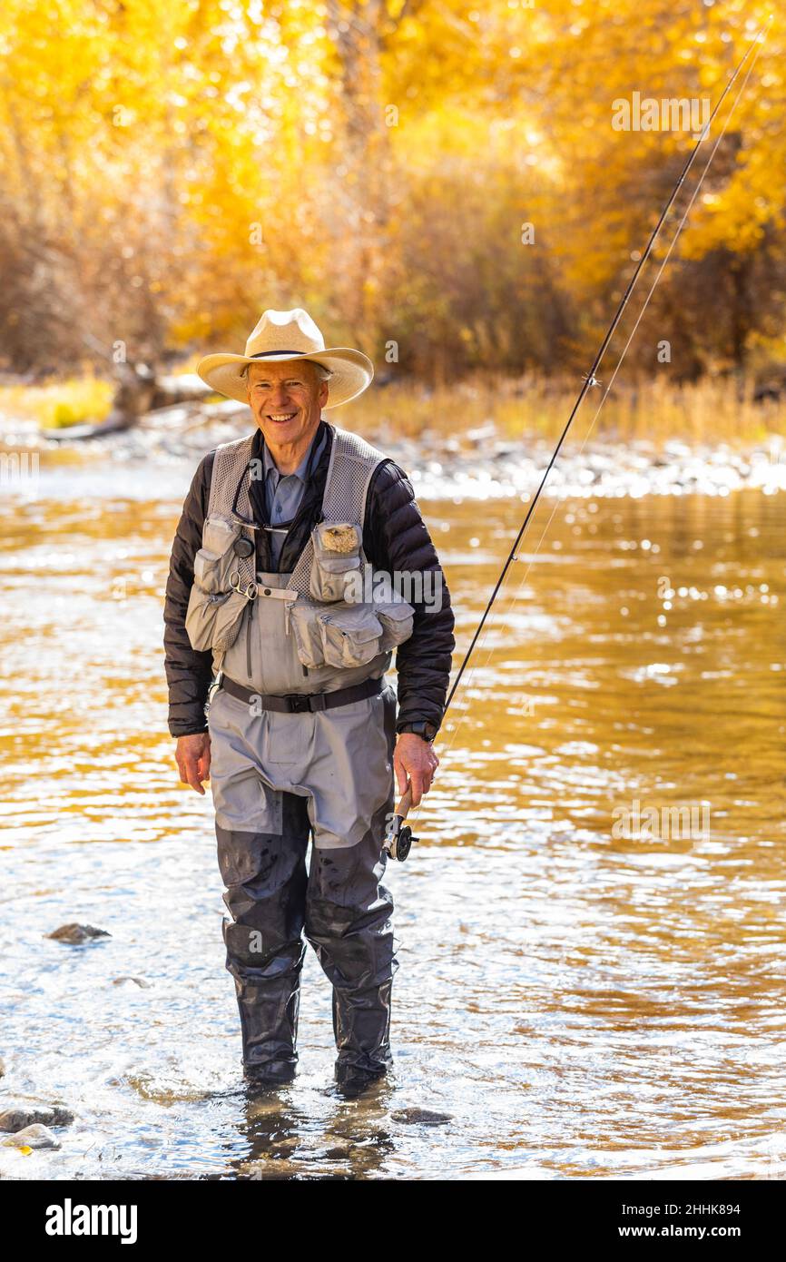 USA, Idaho, Bellevue, Portrait of smiling senior man fly fishing in Big Wood River in Autumn Stock Photo