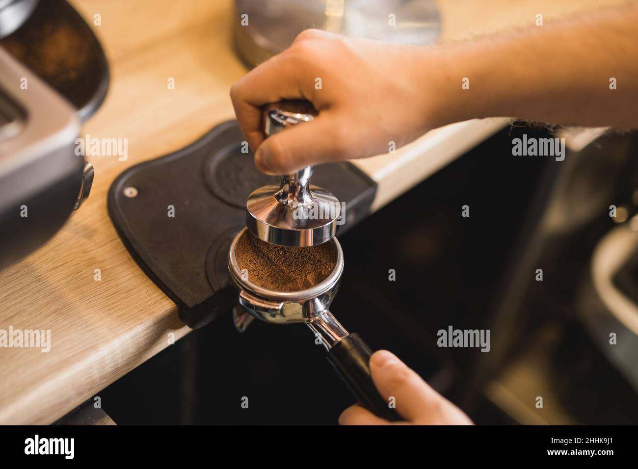 High angle of crop anonymous barista tampering ground aromatic coffee