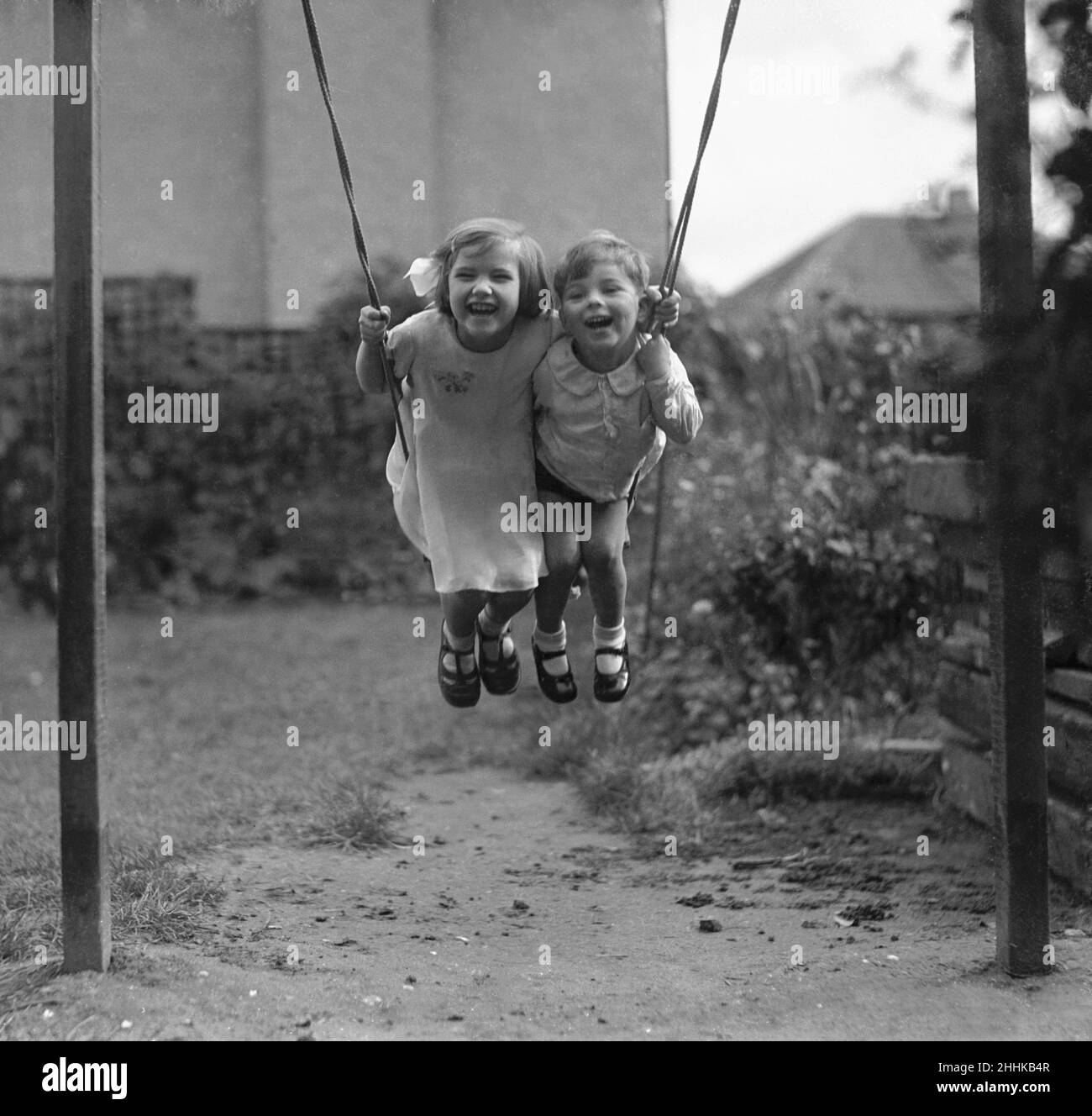 Betty Graves and Keith having fun on a back garden swing Alfieri. 1277. Child Studies-Swing. 1/3. (other negs damaged) October 8th 1933. Stock Photo