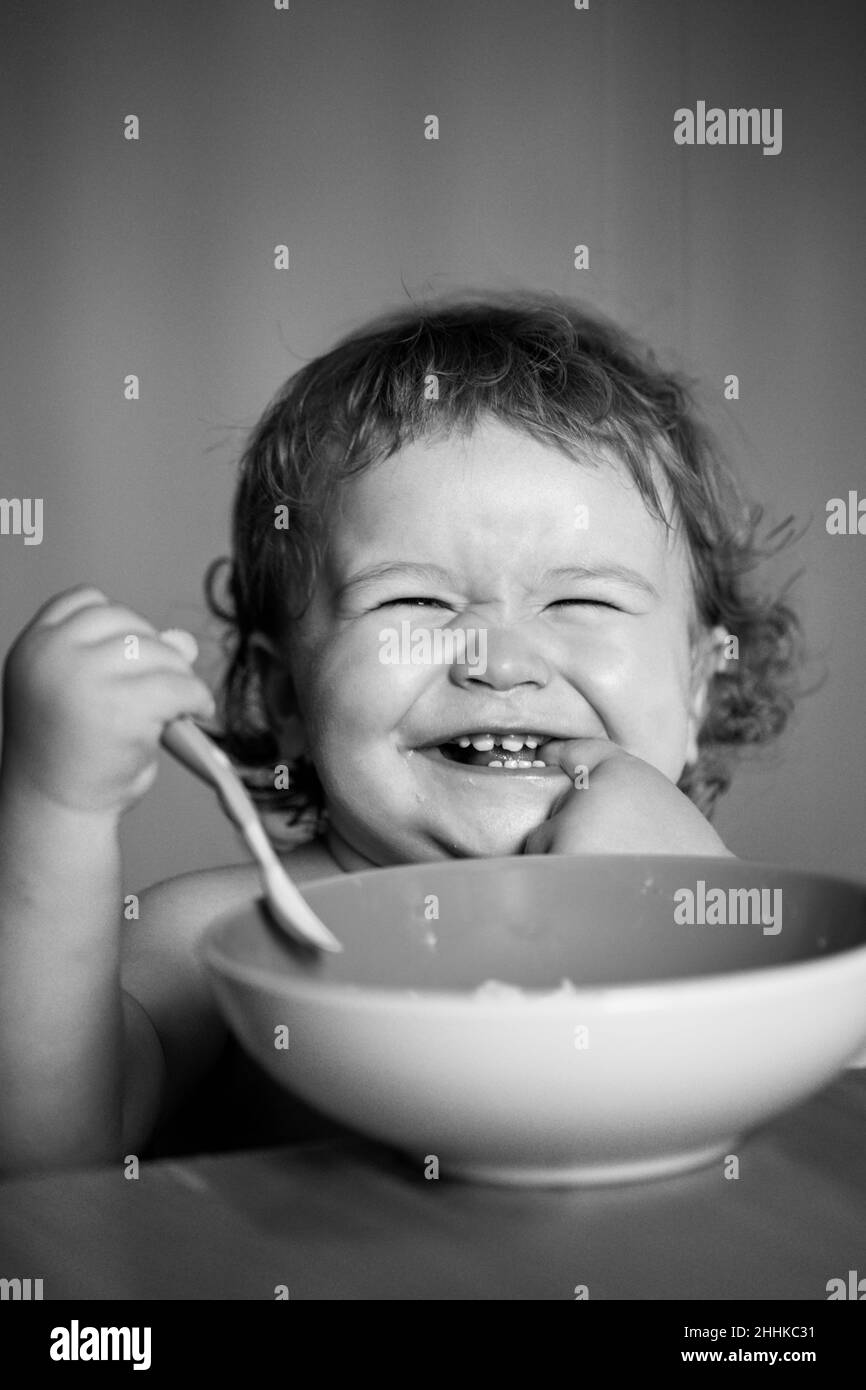 Smiling baby eating food. Launching child with spoon Stock Photo - Alamy