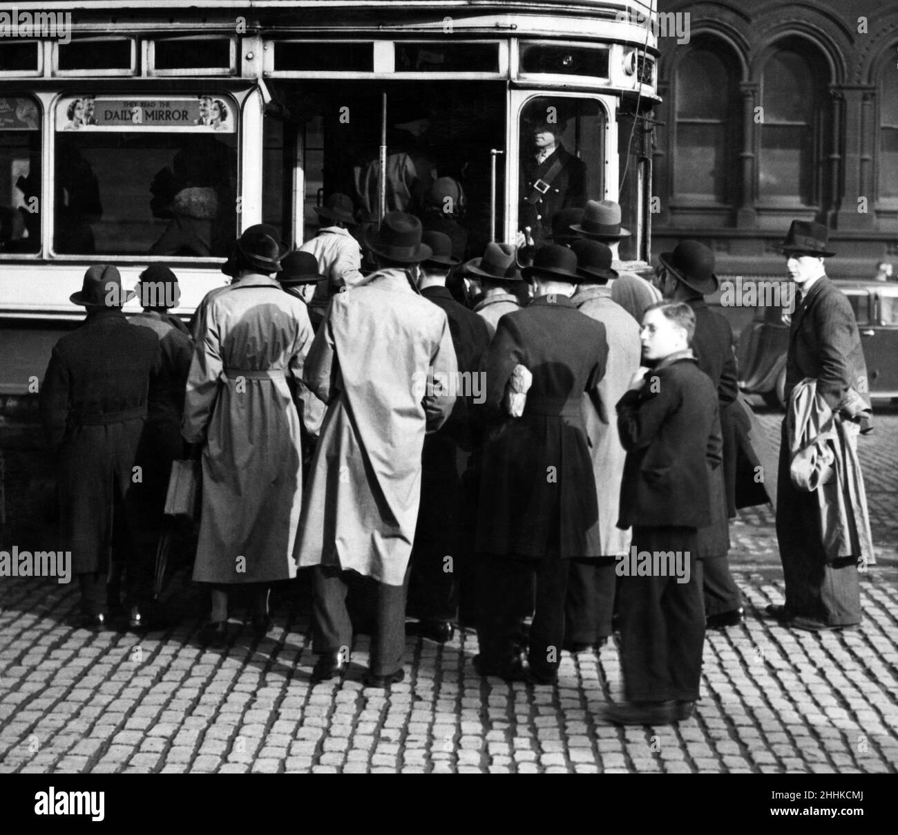 In the mid 1930s, the Manchester Corporation tried to make the passengers for trams enter the vehicles in an orderly queue. Rails were placed at the stops, but as this picture shows, the Manchester public were having none of it. But that independent spirit was changed later when the discipline of war made rules and regulations more strict. Albert Square, Manchester. Circa 1935. Stock Photo