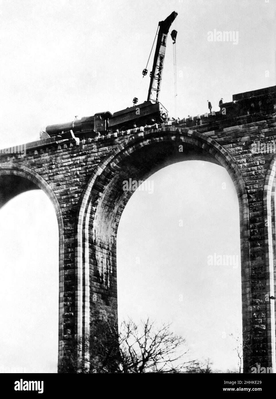 The nightmare of a train crash on a viaduct happened on the Great Western Railway's northern mainline, near Cefn and Chirk, Vale of Llangollen in March 1928. A goods train's guard cheated death by hanging onto the parapet 150ft above the river below after his van caught fire in a collision between two trains.  A breakdown crane here attends to the GWR 2-8-0 freight loco, which lost its chimney in the crash.  Several trucks had smashed through the parapet, falling into the river.  P001150 Stock Photo