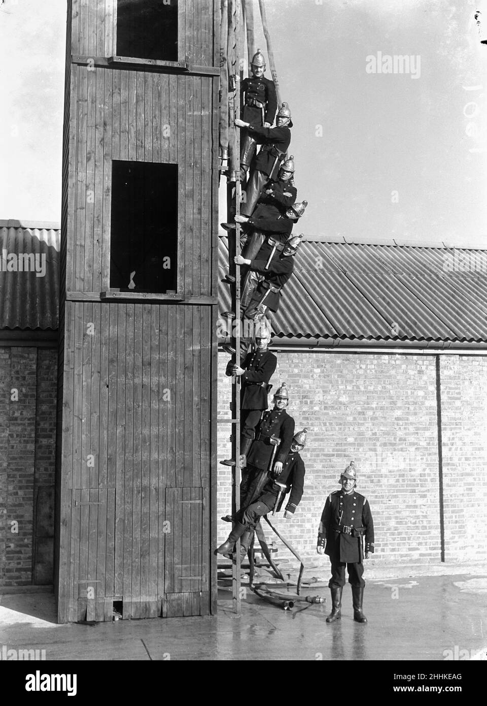 Surbiton Fire Brigade Display . October 1933The Bridgade pose on a ladder beside their training tower Stock Photo