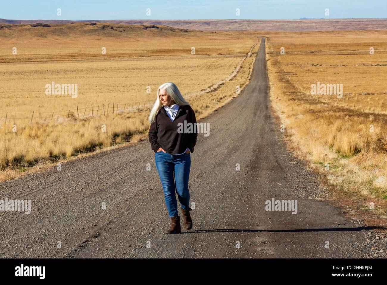 USA, Nevada, Winnemucca, Senior woman walking down desert road Stock