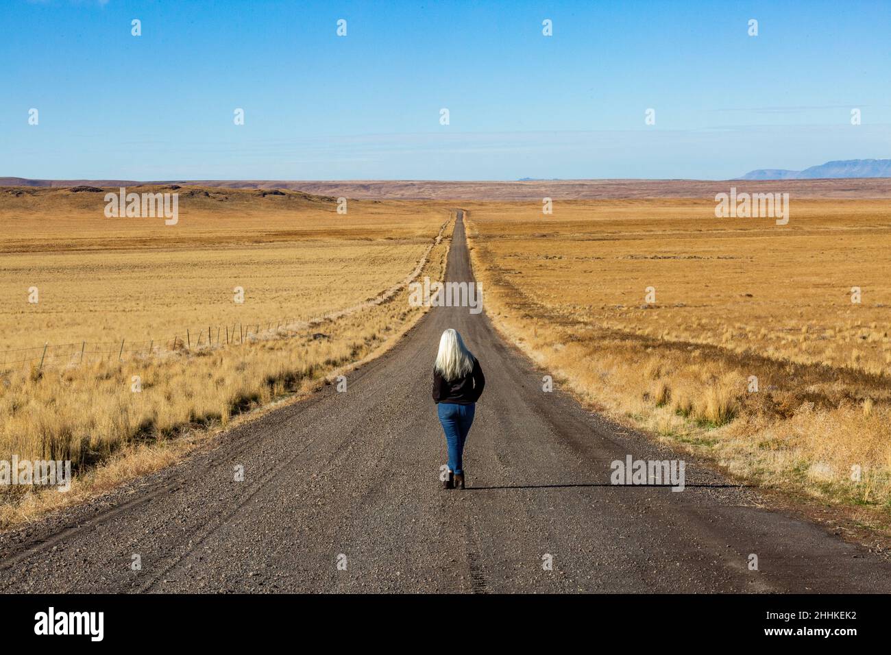 USA, Nevada, Winnemucca, Senior woman walking down desert road Stock