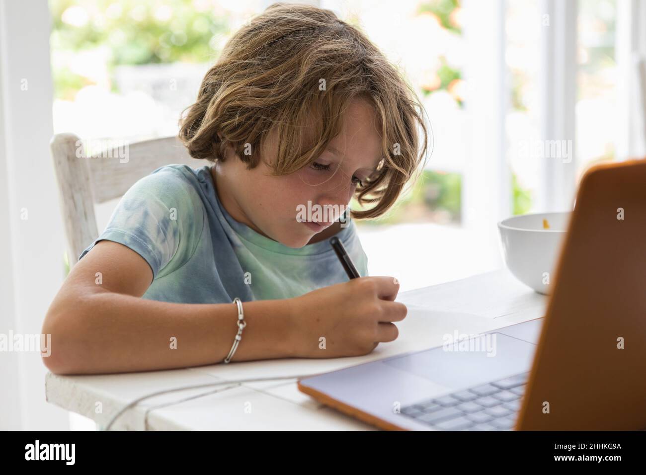Boy (8-9) drawing picture during online lesson Stock Photo