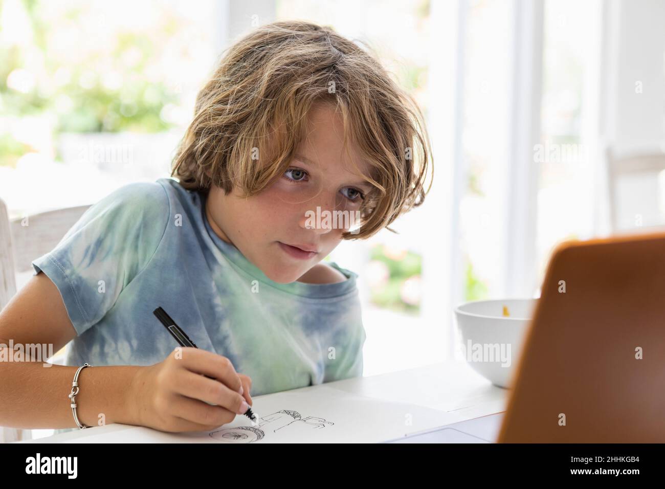 Boy (8-9) drawing picture during online lesson Stock Photo