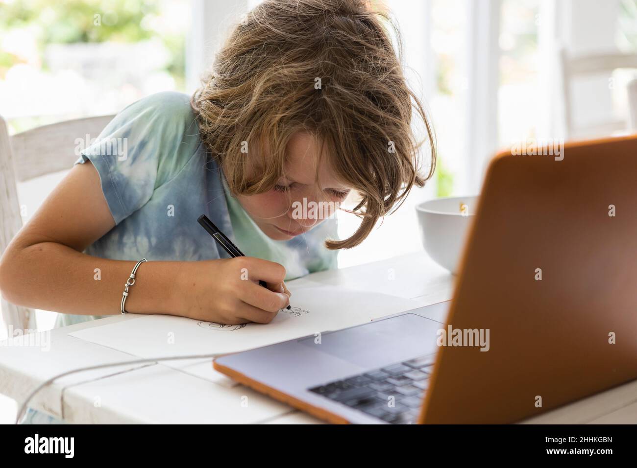 Boy (8-9) drawing picture during online lesson Stock Photo