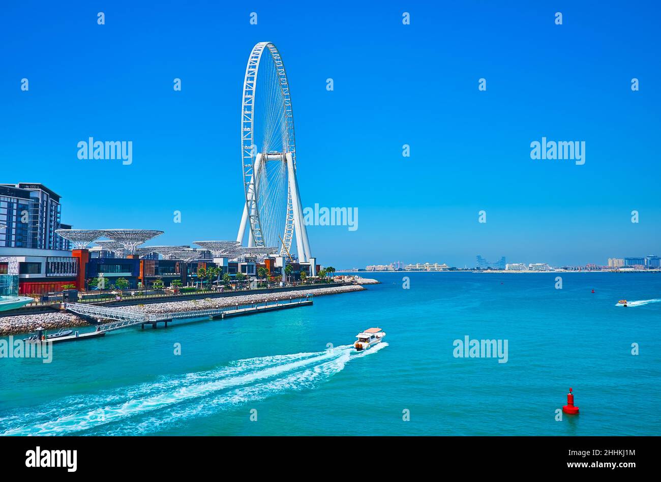 The coast of Bluewaters Island with modern Ain Dubai ferris wheel and the boats, floating from Marina, Dubai, UAE Stock Photo