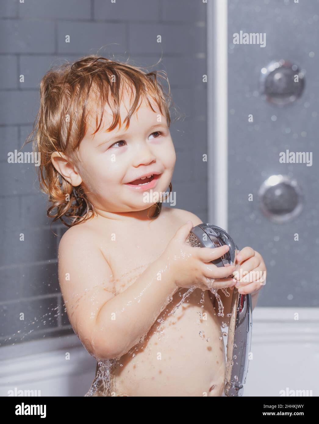 Child bathing under a shower. Funny baby kid bathed in foam and washing