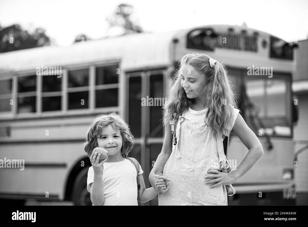 Back to school. Photo of two happy children looking out the windows of a yellow school bus. Plenty of space for text. Stock Photo