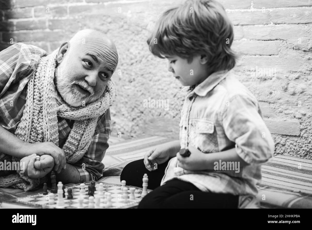 Senior man thinking about his next move in a game of chess. Grandfather and grandson playing chess. Grandfather playing chess with his grandson. Stock Photo