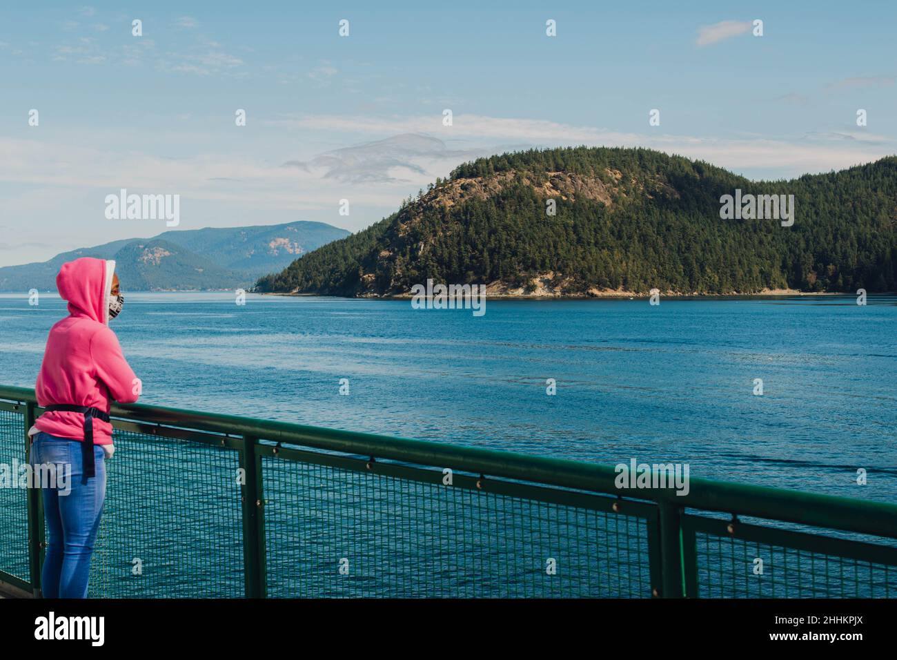 woman in pink sweatshirt and face mask on ferry boat in San Juan Islands Stock Photo