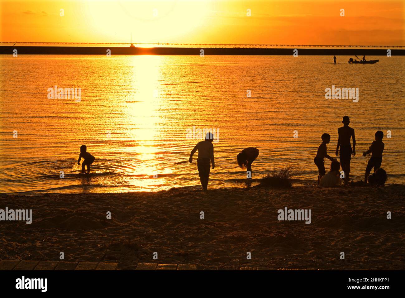 Children splash in Lake Pontchartrain at sunset Stock Photo