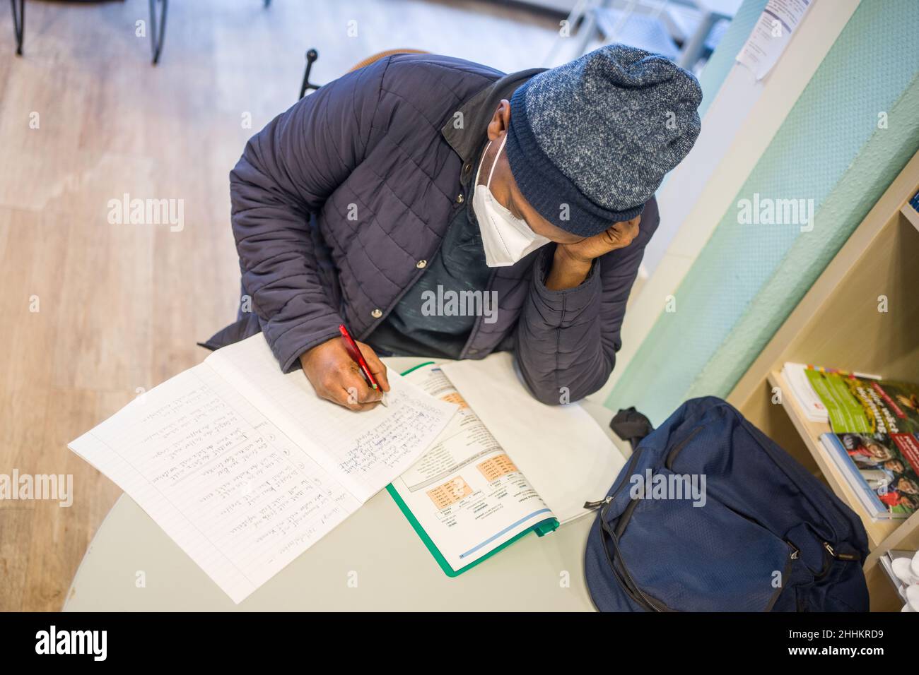 Simmern, Germany. 22nd Jan, 2022. A guest at the Lerncafe in Simmern, who comes from Yemen and has mastered the Arabic script and language, works with a textbook to learn the Latin script and German language and grammar. The learning cafe is a free service run by GruBiNetz, the basic education network of Rhineland-Palatinate. (to dpa 'Written language in Corona everyday life - A hurdle for millions of adults') Credit: Frank Rumpenhorst/dpa/Alamy Live News Stock Photo