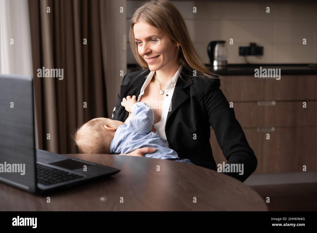 young mother breastfeeding a baby working remotely at home, a woman
