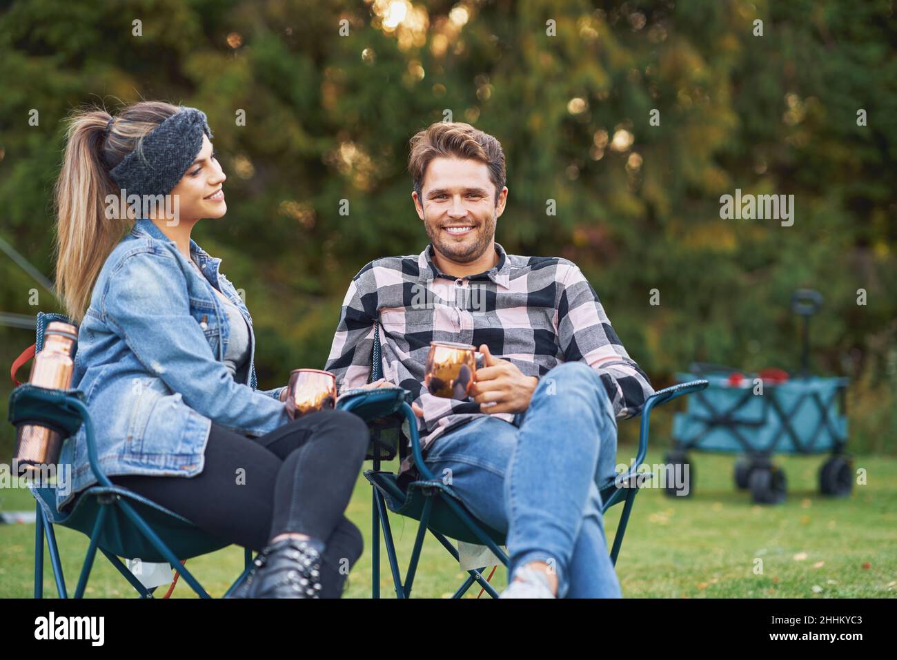 Young nice couple sitting on chairs inf front of tent on camping Stock ...