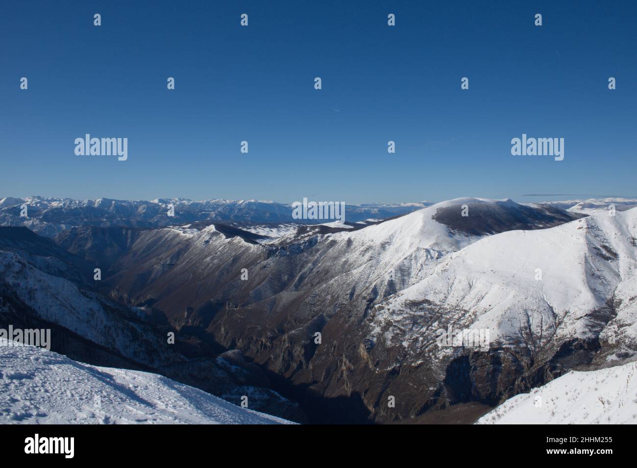 Aerial view of the peaks of snowy mountains under the blue sky Stock ...