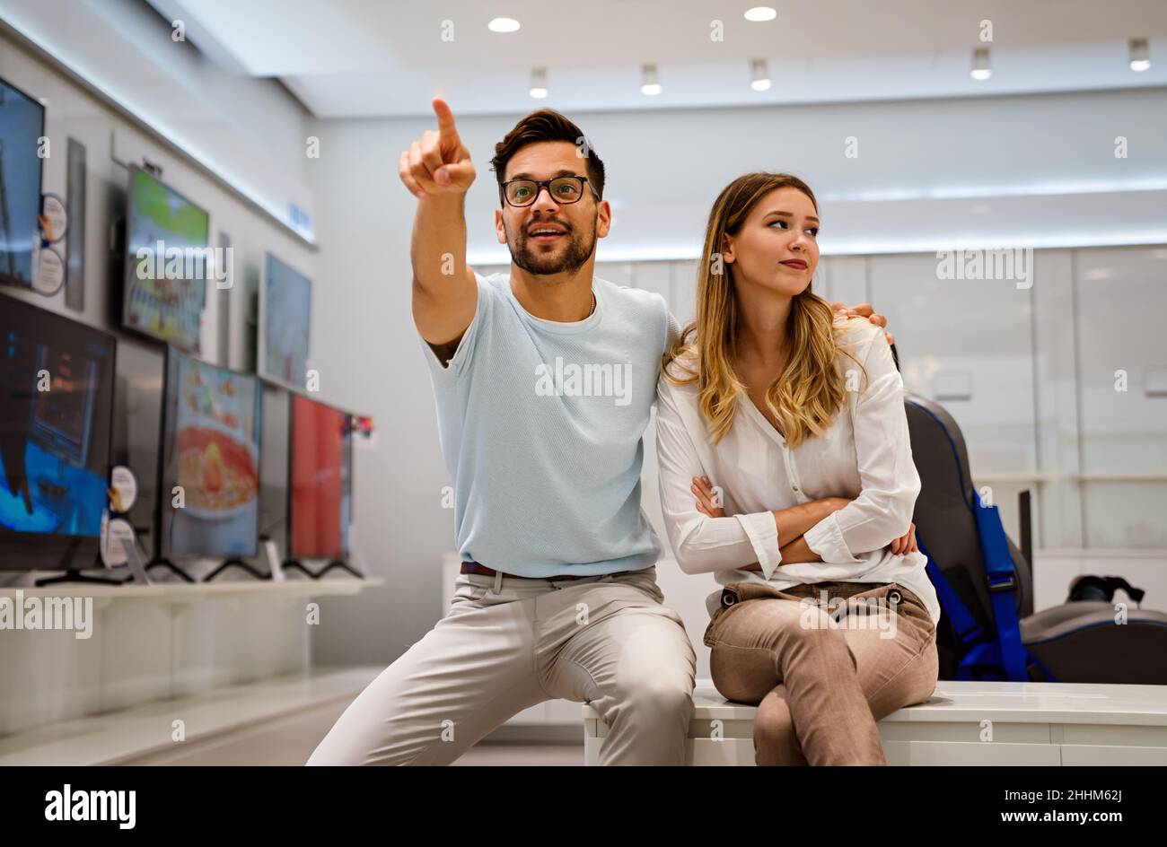 Happy people in consumer electronics retail store looking at new digital device Stock Photo