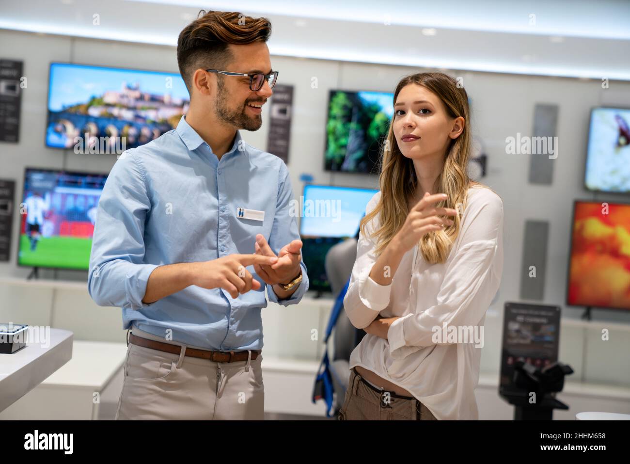 Portrait of salesman helping to woman to buy a new digital device in tech shop Stock Photo