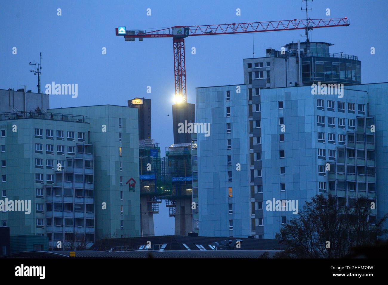 Magdeburg, Germany. 25th Jan, 2022. The morning dawns over the construction site of the replacement Strombrückzug, which can be seen behind high-rise residential buildings. The day remains cloudy and dry, as in previous days. Credit: Klaus-Dietmar Gabbert/dpa-Zentralbild/ZB/dpa/Alamy Live News Stock Photo