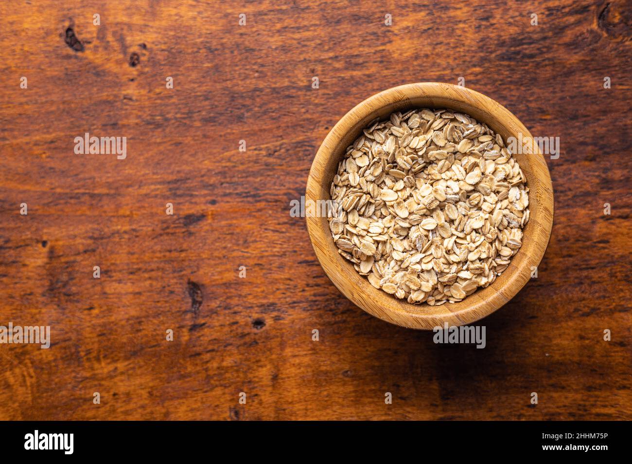 Breakfast cereals. Uncooked oatmeal. Raw oat flakes in bowl on wooden table. Top view. Stock Photo