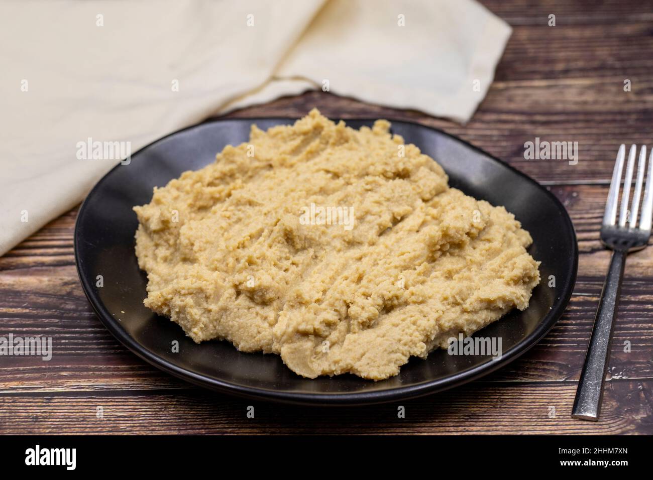 Hummus in a ceramic plate. Dishes of chickpeas, a vegetarian dish. Stock Photo