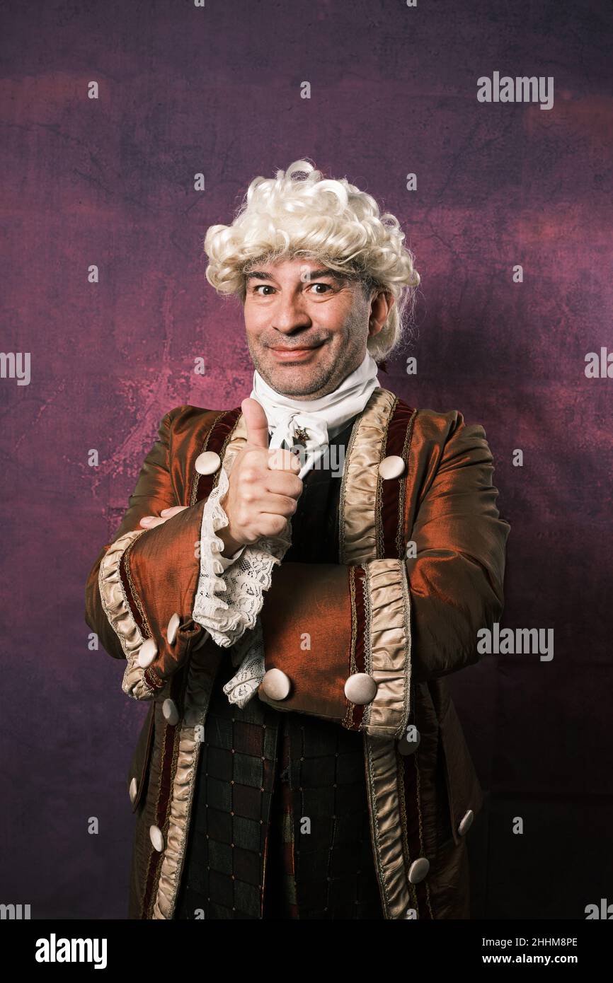 Adult man in classical medieval clothing showing thumb up while standing on an isolated background. Stock Photo