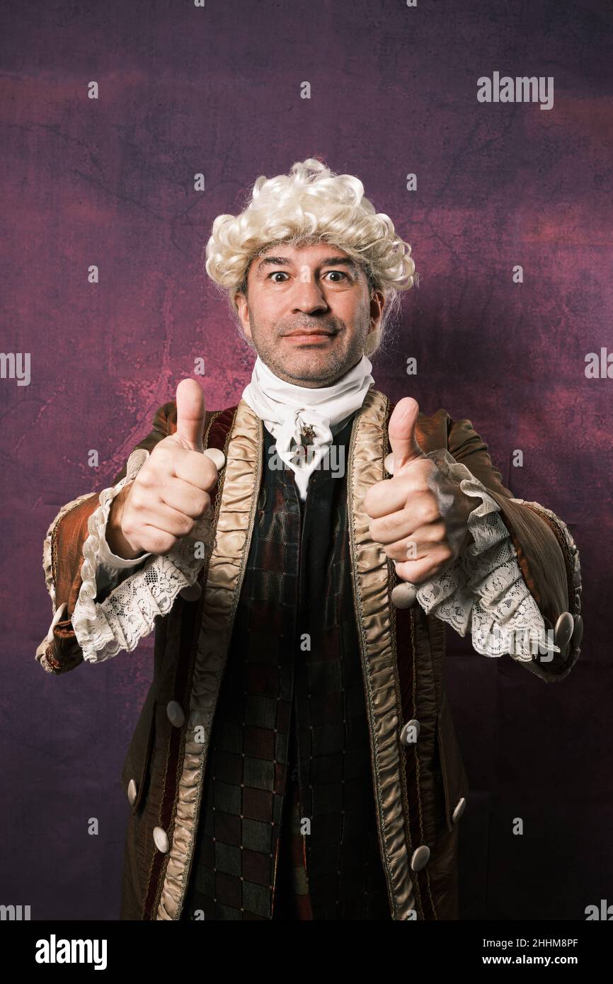 Man in classic renaissance clothes showing thumbs up to camera. Stock Photo