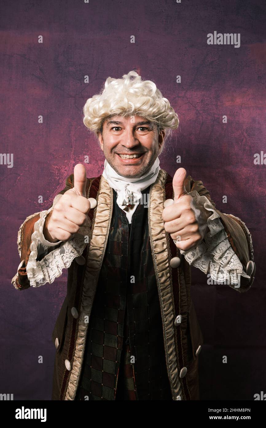 Smiling man in classic medieval clothes showing thumbs up to camera. Stock Photo
