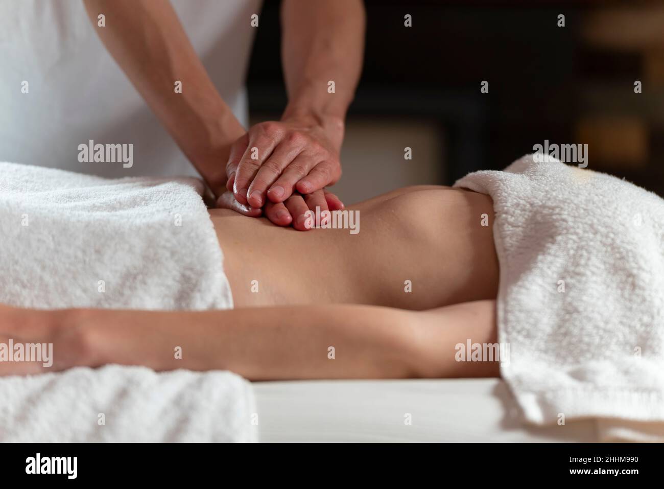 A masseuse woman doing an oil massage to another woman on the stomach Stock Photo