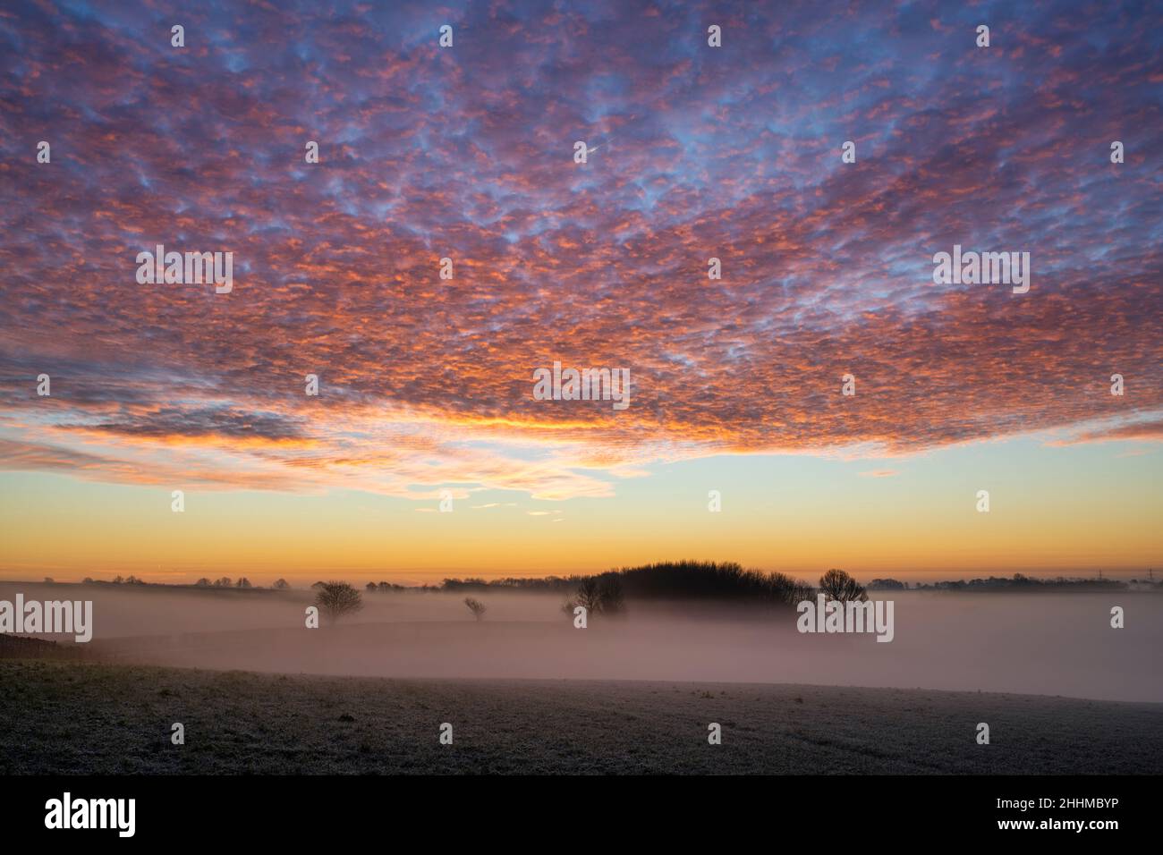 Winter red sky and mist just before sunrise in the frosty cotswold