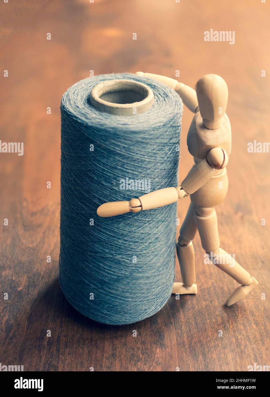 Wooden mannequin holds cone with knitting yarn, upright format. Concept of craftsmanship, needlework, weaving Stock Photo