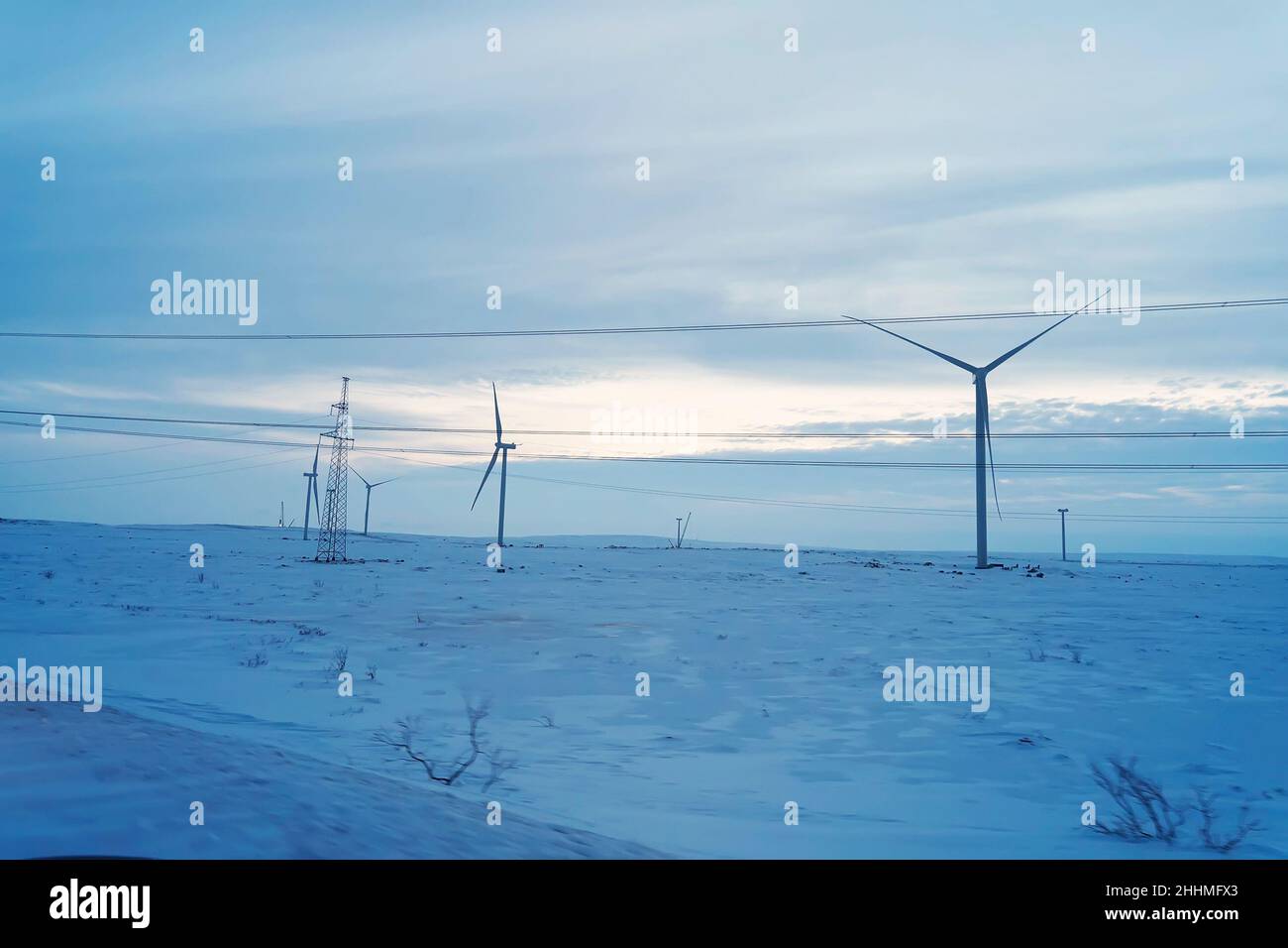 Snowy field and wind turbine at sunrise in winter. Aerial view of ...