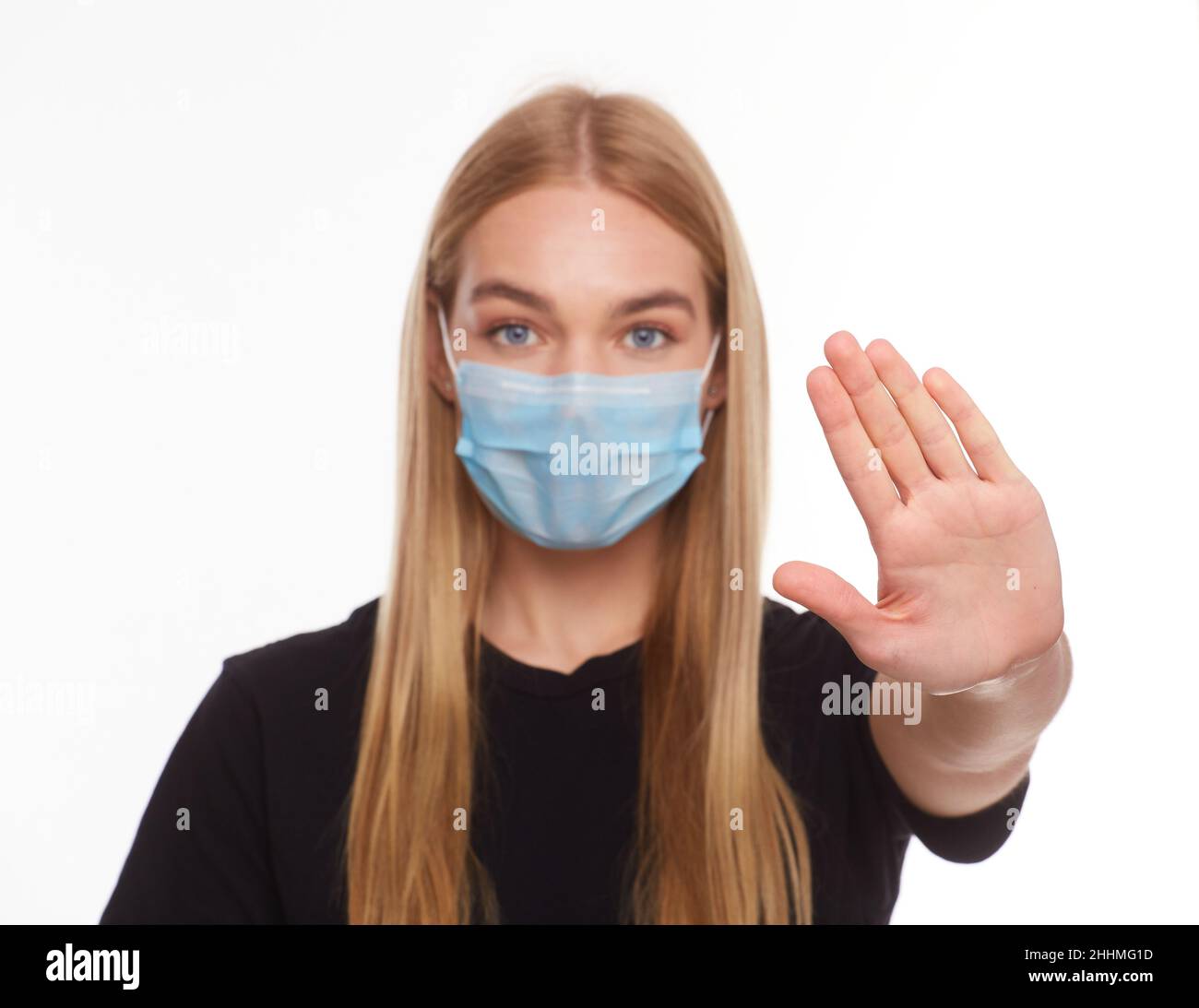 young woman in medical protective mask shows a stop gesture with hand ...