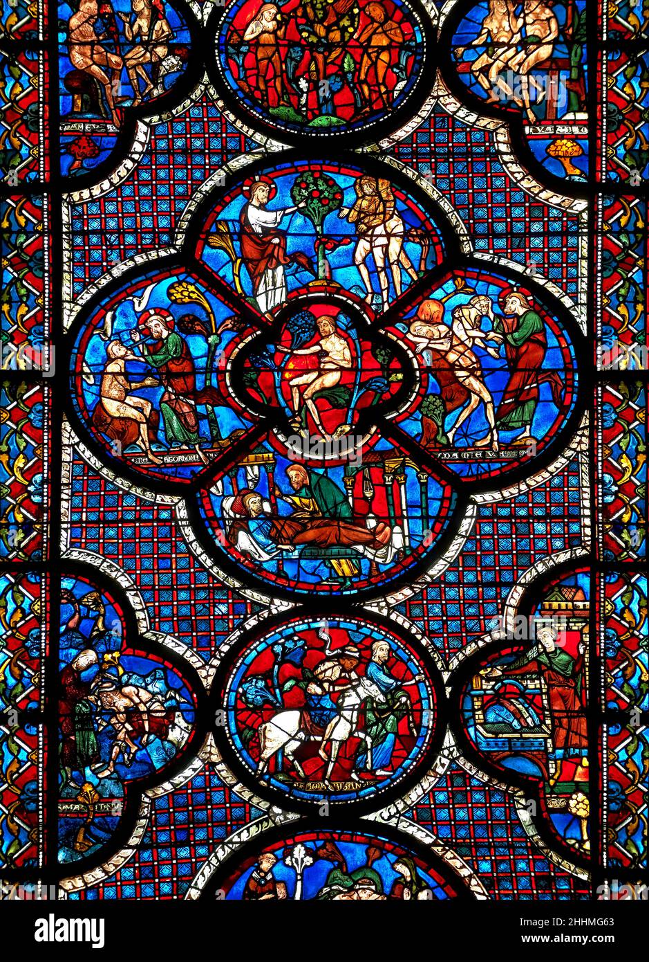 Medieval stained glass Window of the Gothic Cathedral of Chartres, France - dedicated to the Good Samaritan . Central panel shows Adam dwelling in Par Stock Photo