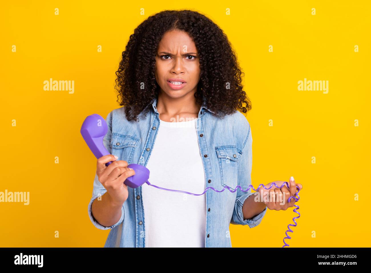 Photo of angry unhappy upset young afro american woman hold hand telephone bad mood isolated on yellow color background Stock Photo