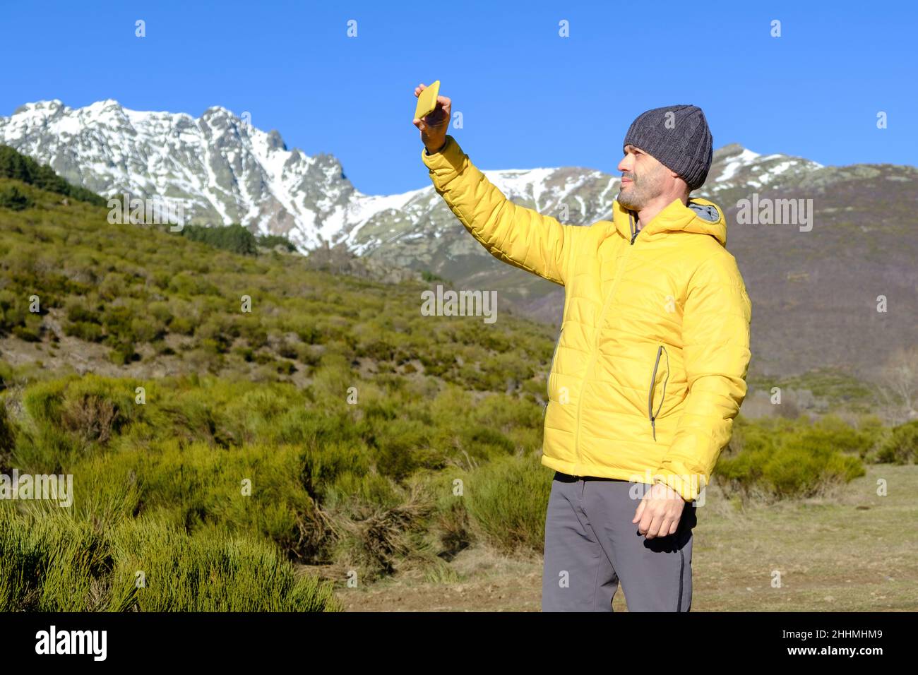 A man takes a selfie with his smartphone in the snowy mountains. Enjoying nature alone Stock Photo
