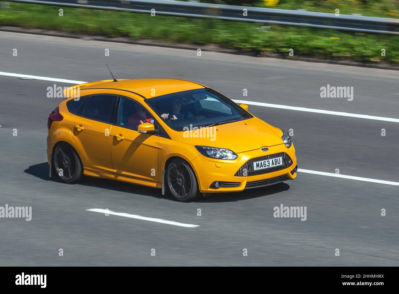2013 Orange Ford Focus ST-2 1999cc 6-speed manual vehicular traffic, moving vehicles, petrol classic sports car, English, England, uk roads, motors, motoring, moving, cars driving vehicle, being driven, transport, travel, cars driving vehicle in motion, UK Stock Photo
