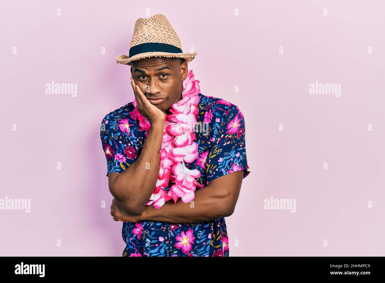 Young black man wearing summer shirt and hawaiian lei thinking looking ...
