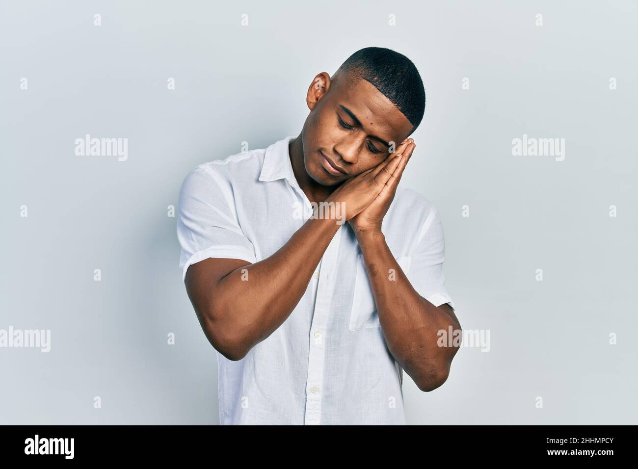 Young black man wearing casual white shirt sleeping tired dreaming and ...
