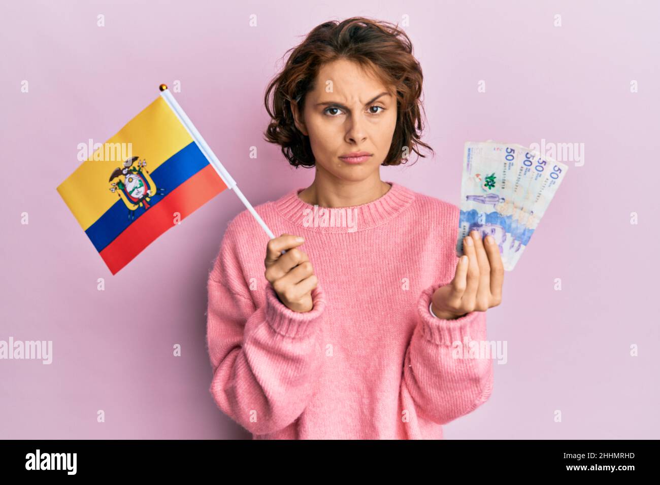 Young brunette woman holding colombia flag and colombian pesos ...
