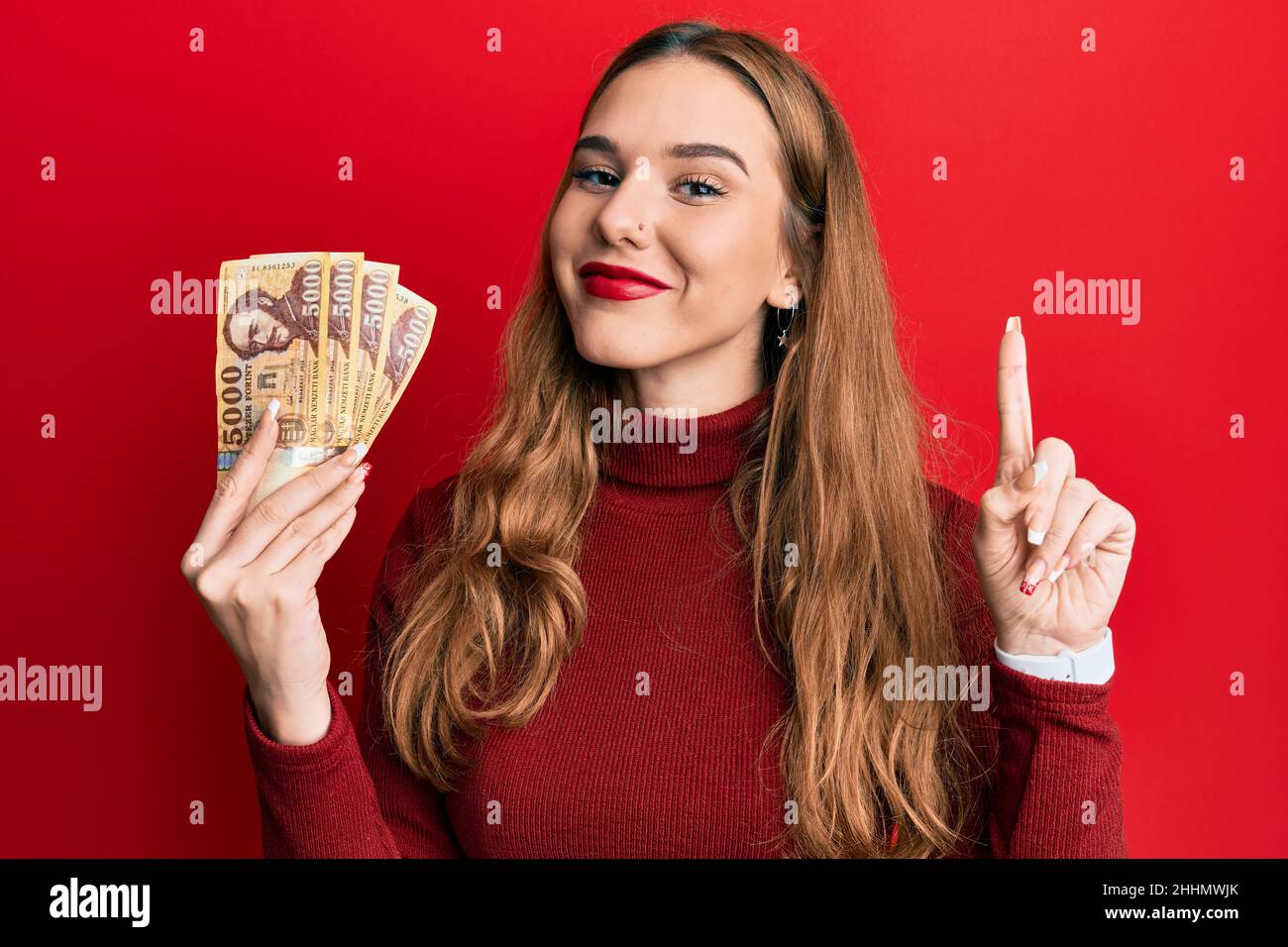 Young Blonde Woman Holding 5000 Hungarian Forint Banknotes Smiling With An Idea Or Question